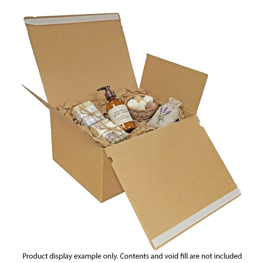 Open cardboard box with bath products including a bottle, soap, and candles on a white background.