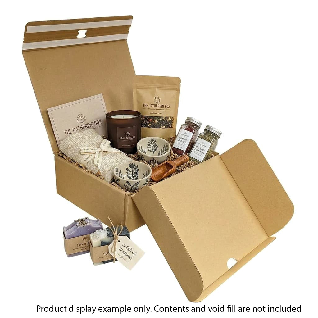Open cardboard gift box with various items including a candle, plants, and packaging on a white background.