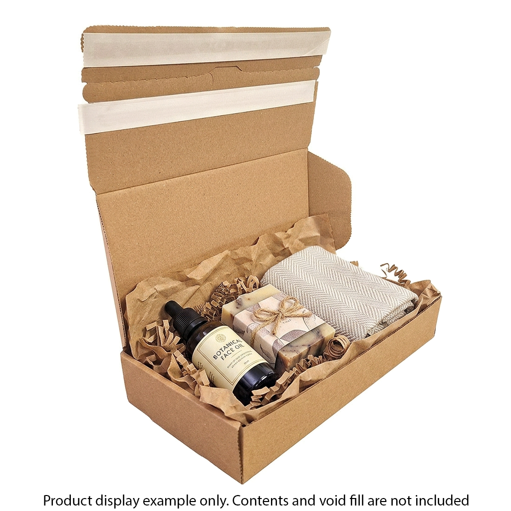Open cardboard box with bath products including a bottle, soap, and towel on a white background.