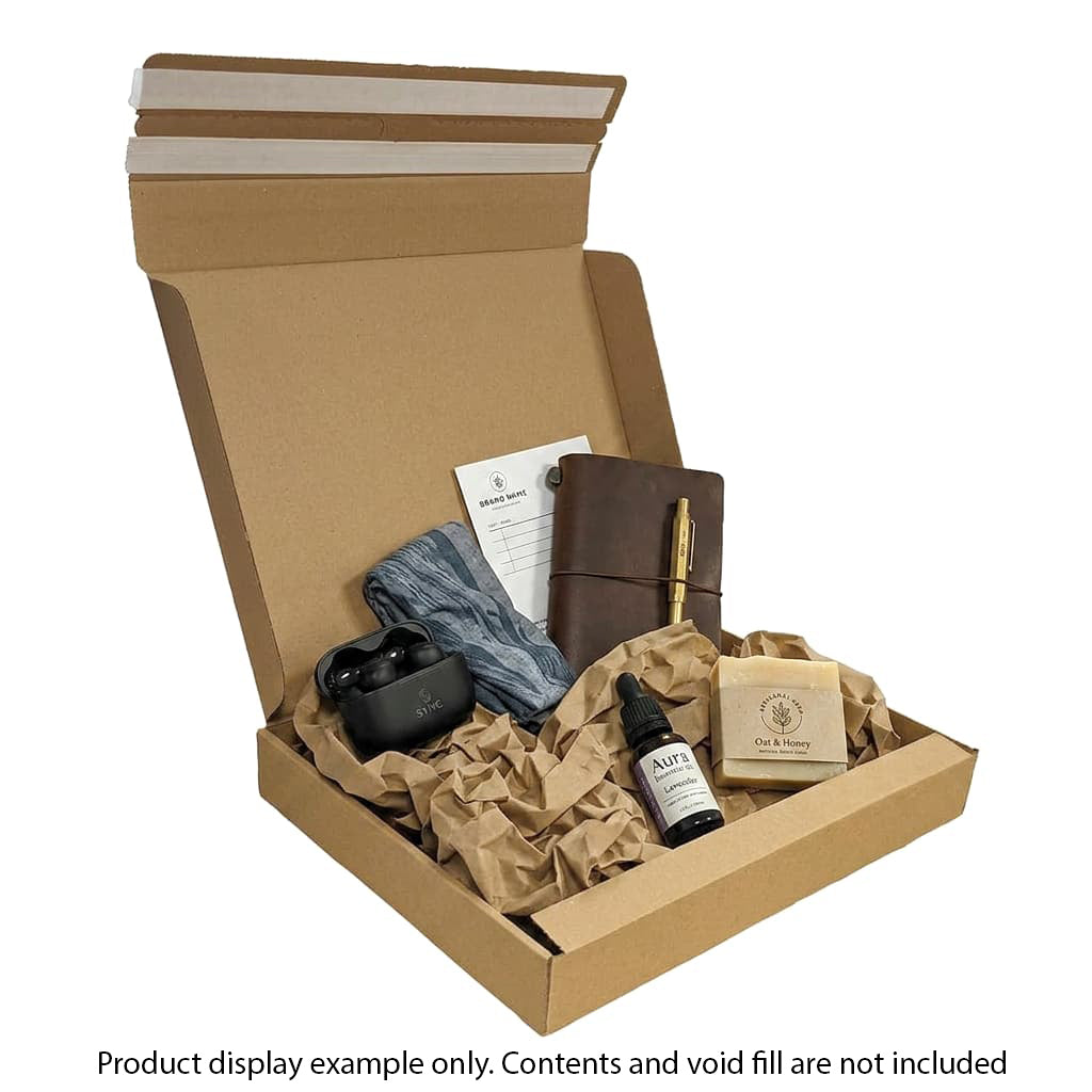 Open cardboard box with various items including a leather journal, pen, and other products on a white background.